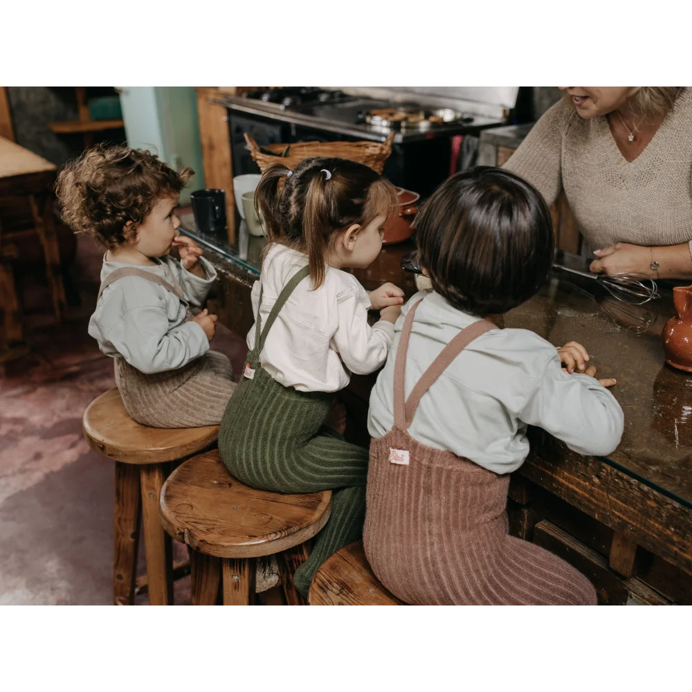 Drei Kinder auf Holzschemel am Tisch, tragen Granny Teddy Strumpfhosen in Peanut Blend