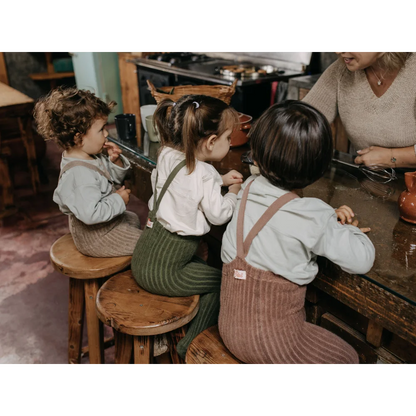 Drei Kinder auf Holzschemel am Tisch, tragen Granny Teddy Strumpfhosen in Peanut Blend