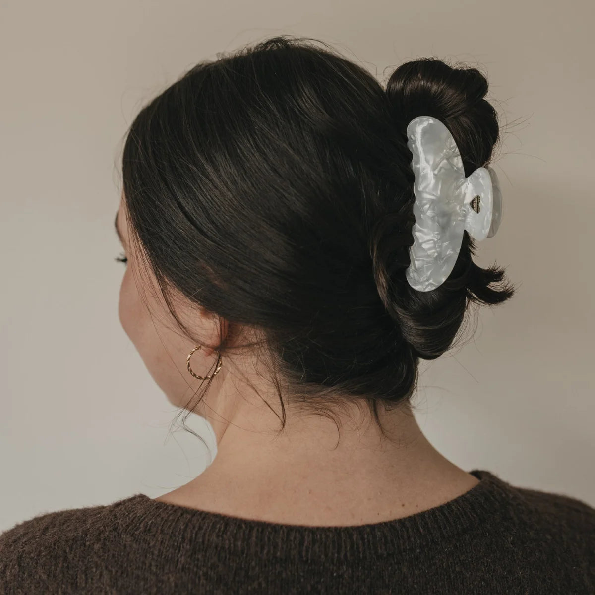 Transparente weiße Haarspange Maxi Herz mit Perle hält dunkles Haar in einem Dutt