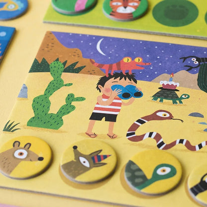 Buntes Kinderrätsel Habitats Lotto: Junge mit Fernglas in Wüste unter Halbmond mit Tieren und Tokens