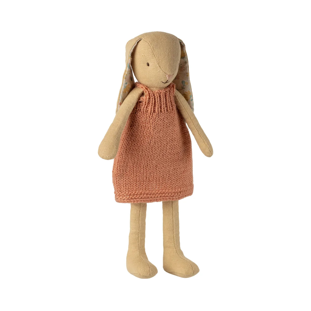 Ein weicher hasen plüschpuppe in strickkleid aus cremegelbem stoff und pfirsichfarbenem gestricktem kleid