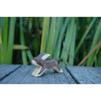 Kleine handgeschnitzte hase laufend Holzfigur mit grauem Körper und hellen Ohren