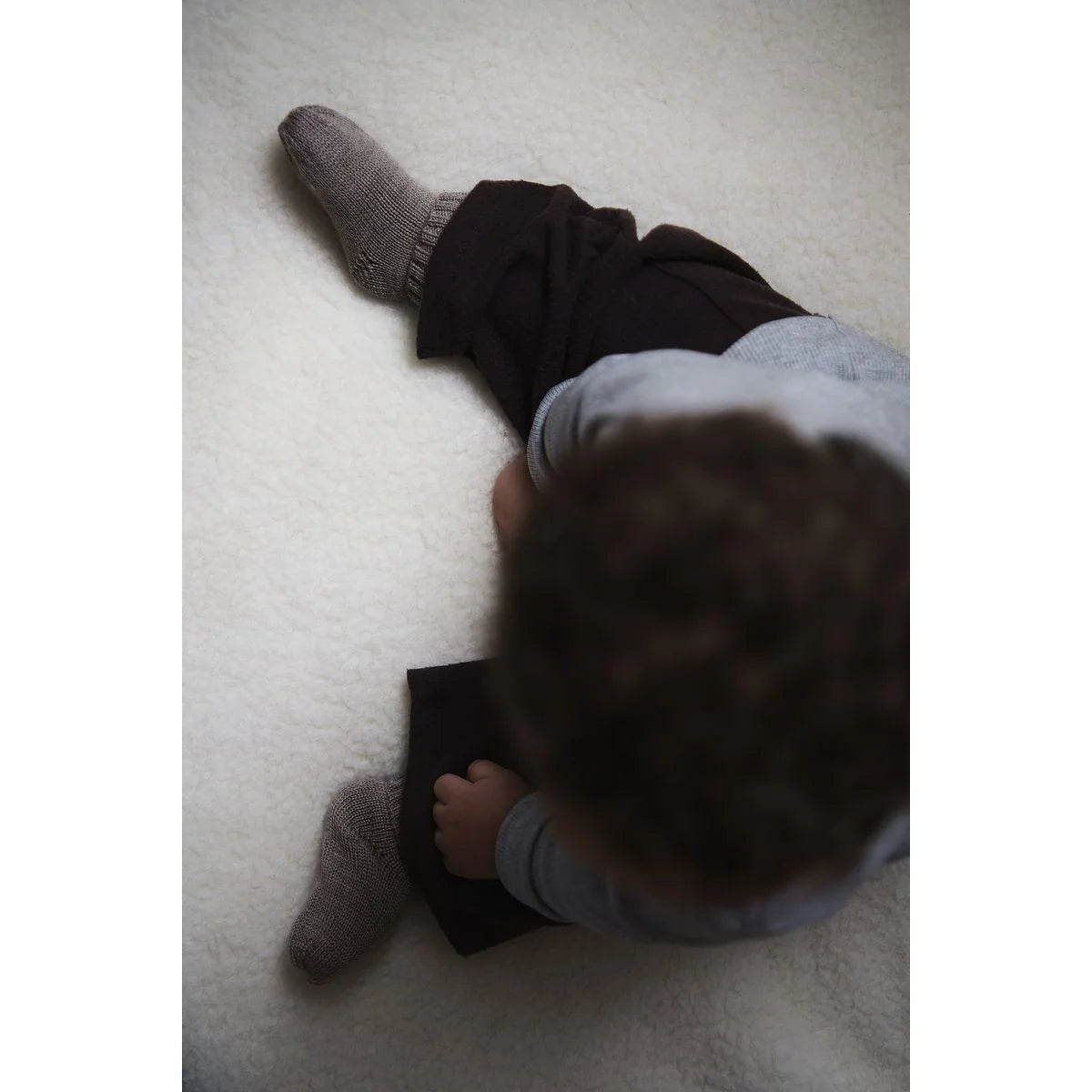 Baby trägt Kico Label Hausschuhe aus Merinowolle in Taupe