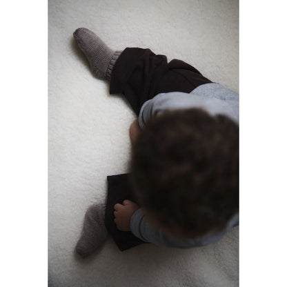 Baby trägt Kico Label Hausschuhe aus Merinowolle in Taupe