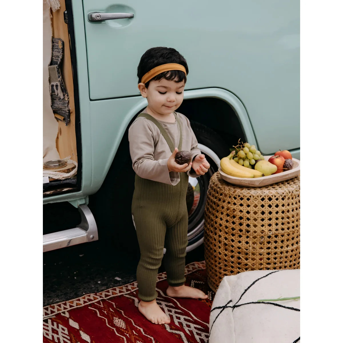 Junges Kind steht neben einem Obstkorb und trägt Hippy Footless Strumpfhosen Olive