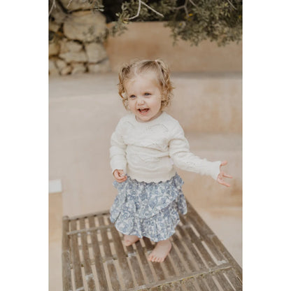 Nachhaltige Babykleidung Schweiz: Kind in weißem Pullover mit Spitze