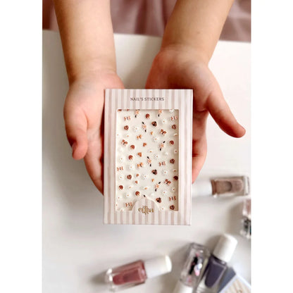 Weiße Kindernageltattoos mit roten Herzen und goldenen Akzenten in gestreiftem Karton