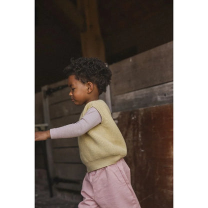 Junge trägt hellgelben Kids Vest Harvey, lila Langarmshirt und rosa Hosen