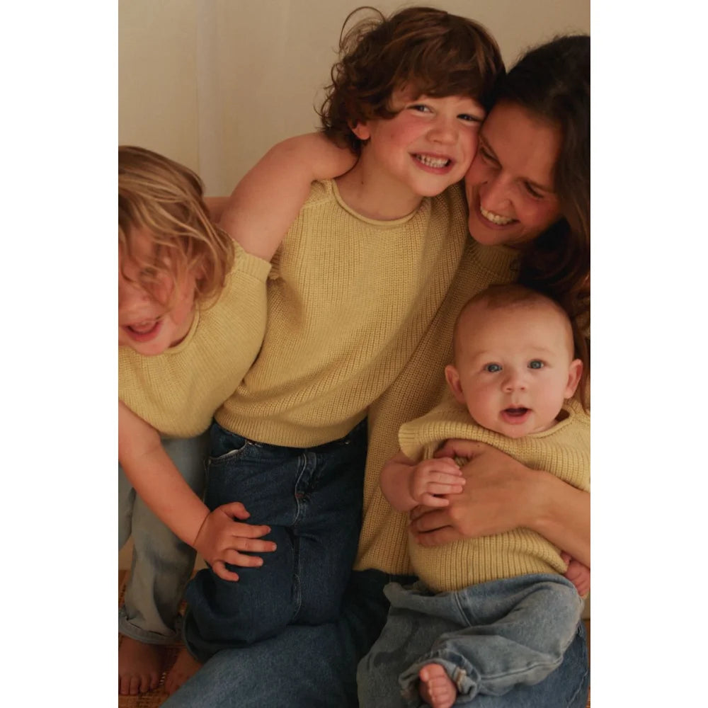 Frau und drei Kinder lachen in gelben Tops und blauen Jeans bei Kids Vest Harvey