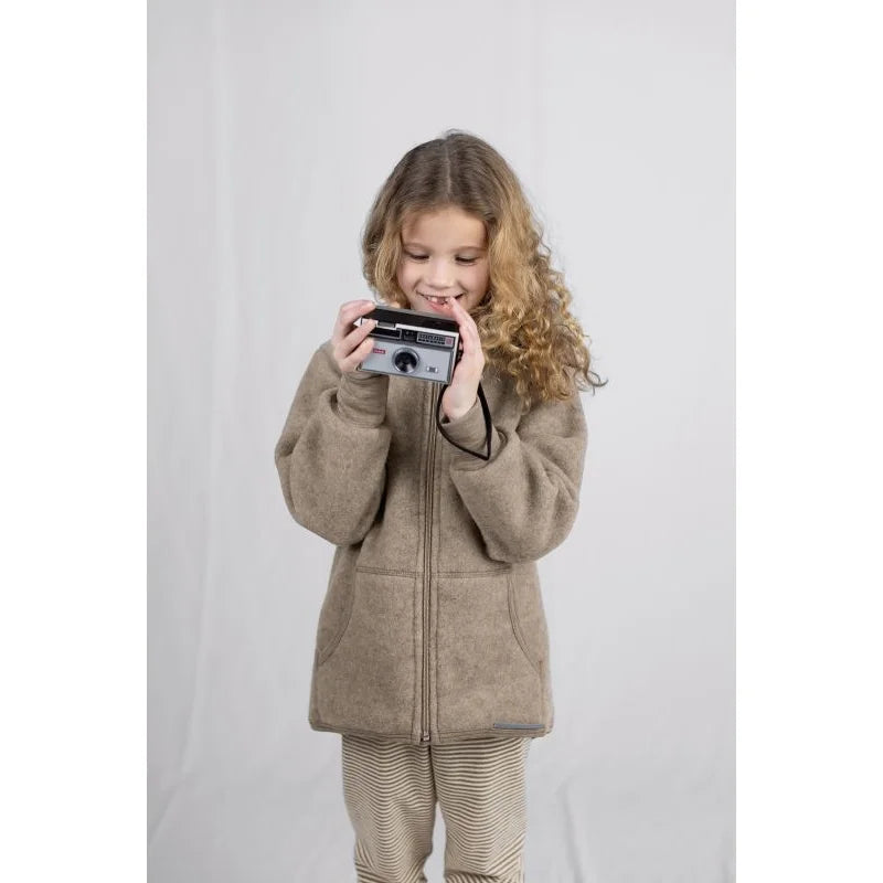 Kind hält vintage silber-schwarze Sofortkamera mit Linse und Drehknöpfen