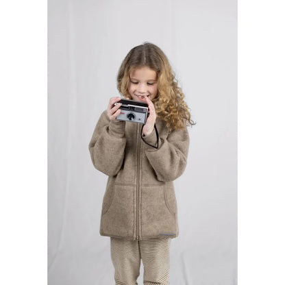 Kind hält vintage silber-schwarze Sofortkamera mit Linse und Drehknöpfen