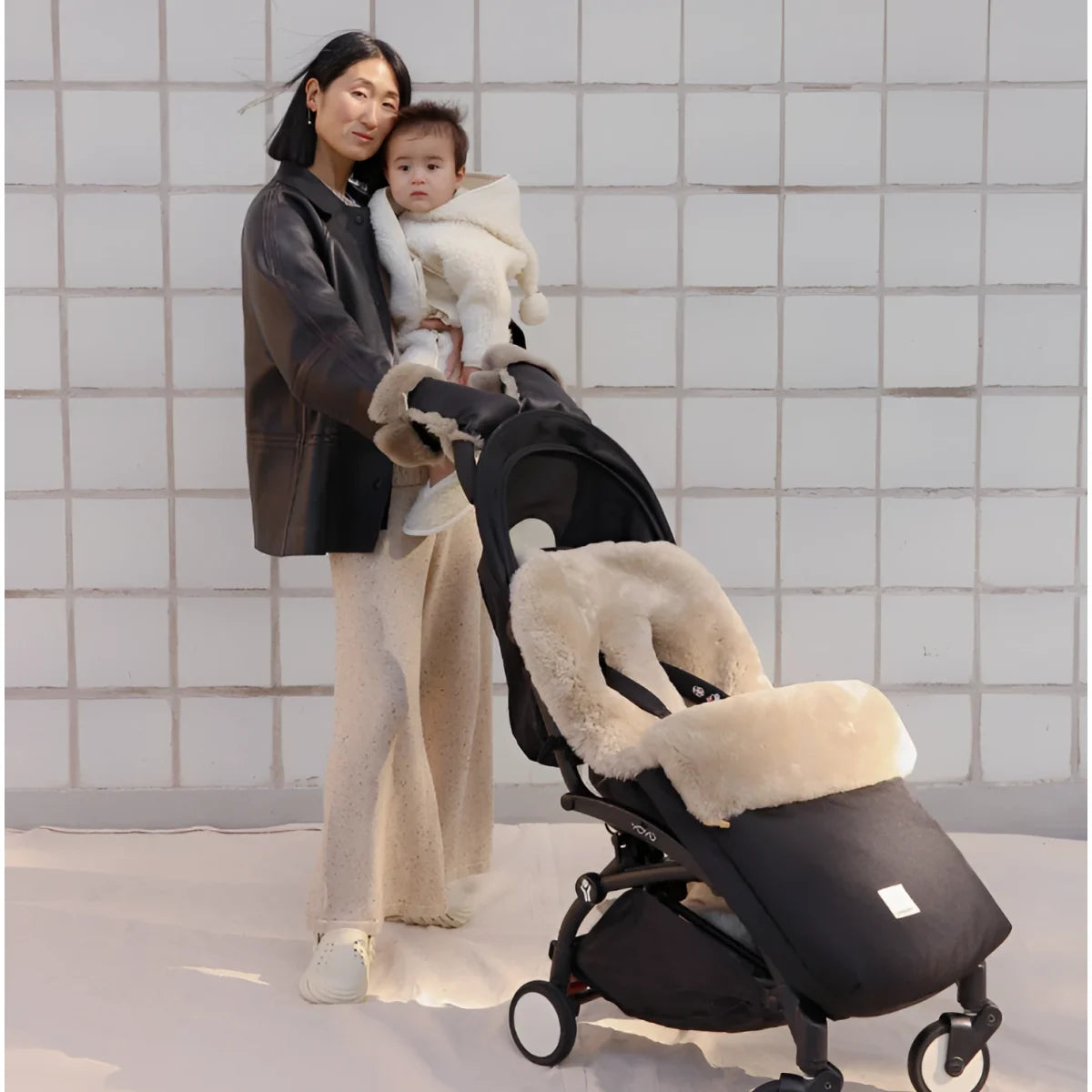 Schwarzer Kinderwagen mit cremefarbenem Kunstfell-Futter, modernem Design, Puffmuff Fusssack und fester Harness in Toast