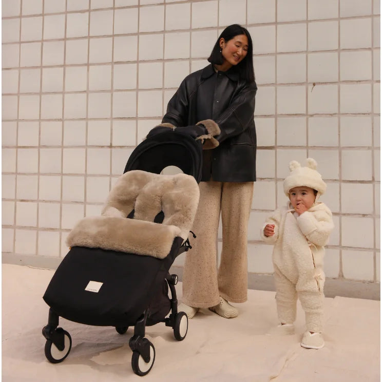 Schwarzer Kinderwagen mit beigefellfutter, weißen Rädern und Toast-Fusssack Puffmuff