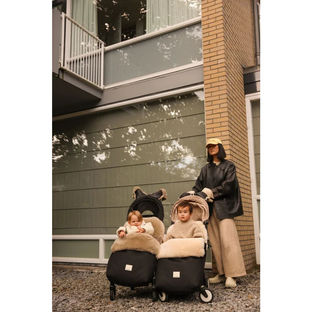 Doppelkinderwagen mit zwei Babys, eingepackt im Fusssack Puffmuff Toast im Winter