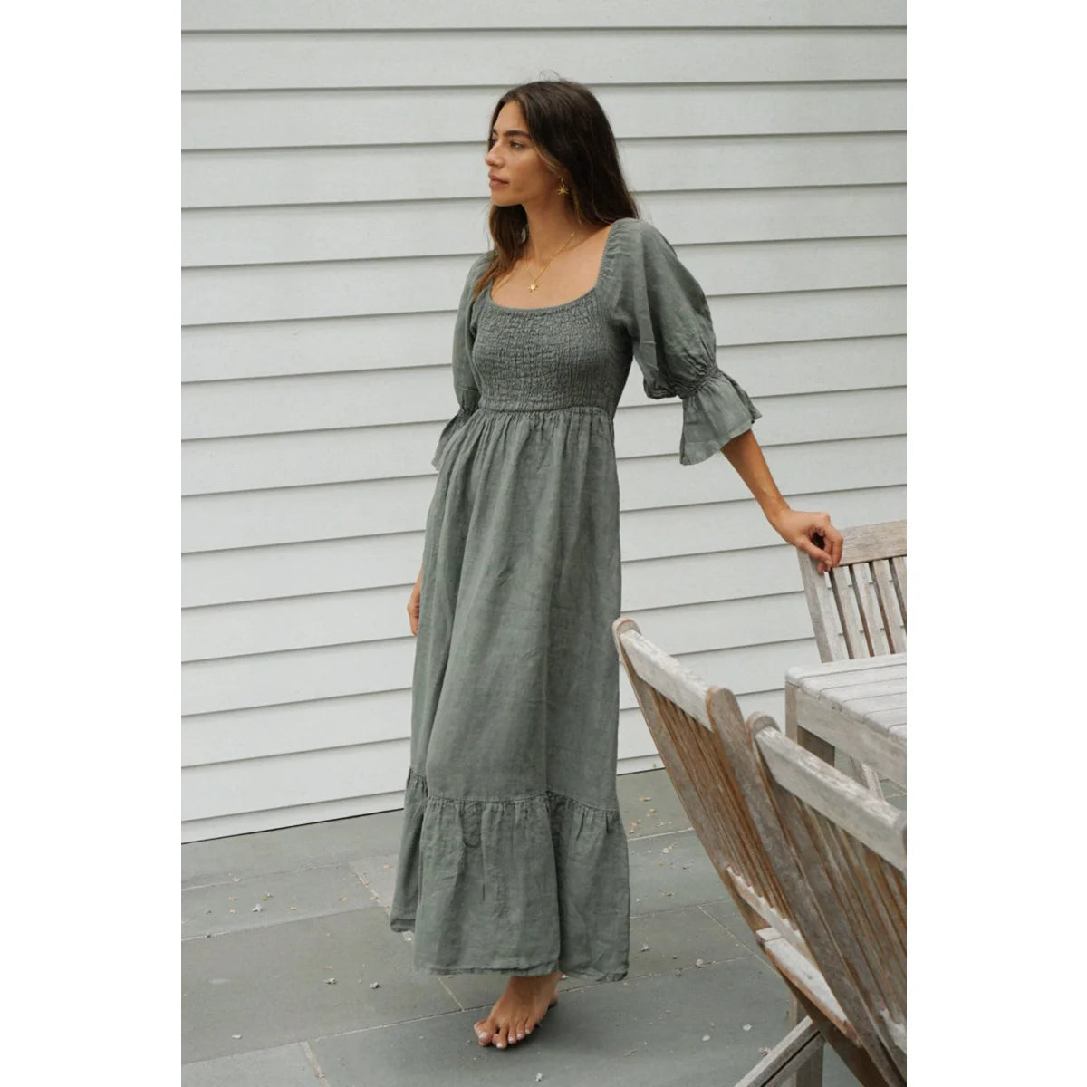 A soft sage green linen midi dress with smocked bodice and puffed sleeves ideal for nachhaltige babykleidung schweiz