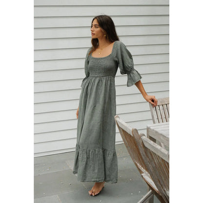 A soft sage green linen midi dress with smocked bodice and puffed sleeves ideal for nachhaltige babykleidung schweiz