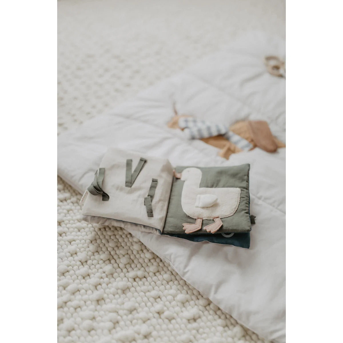 Weiches gefaltetes knisterbuch mit grauem enten-applikation und passenden stoffriemen für ökologische baby- und kinderprodukte