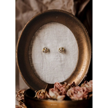 Salma Ohrringe Knoten-Studs in 18k Gold Vermeil auf Leinenkissen im Messingrahmen