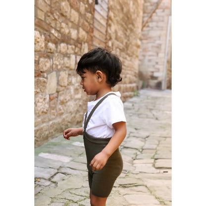 Ein junges kind trägt kurze strumpfhose mit träger seaweed brown in nachhaltige babykleidung schweiz aus ökologischem material