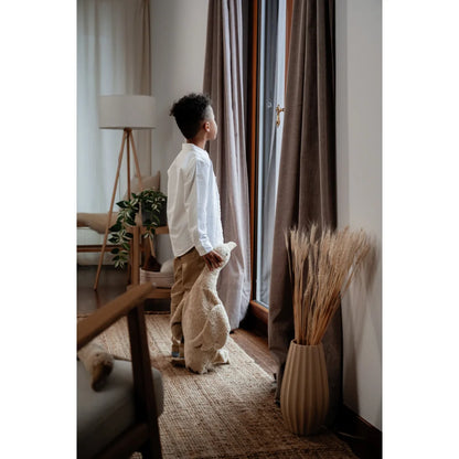 Kind mit Gans-Kuscheltier aus Leinen am Fenster