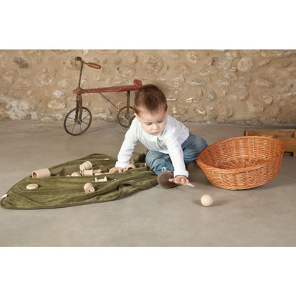 Holzspielboot mit grünem Segel in großem Schatzkorb