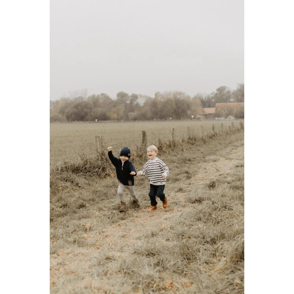 Zwei Jungen rennen im Feld in nachhaltiger Babykleidung Schweiz