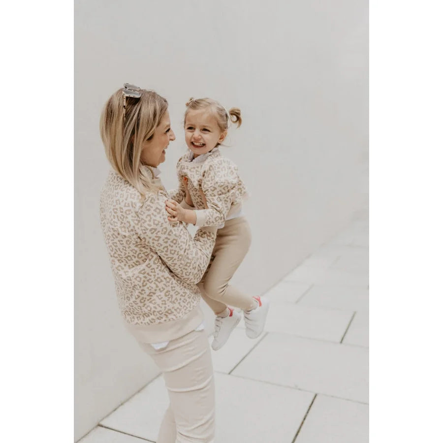 Frau in Leo-Sweatshirt mit verdecktem Kordelzug hält Kind in Leevje Cordhose