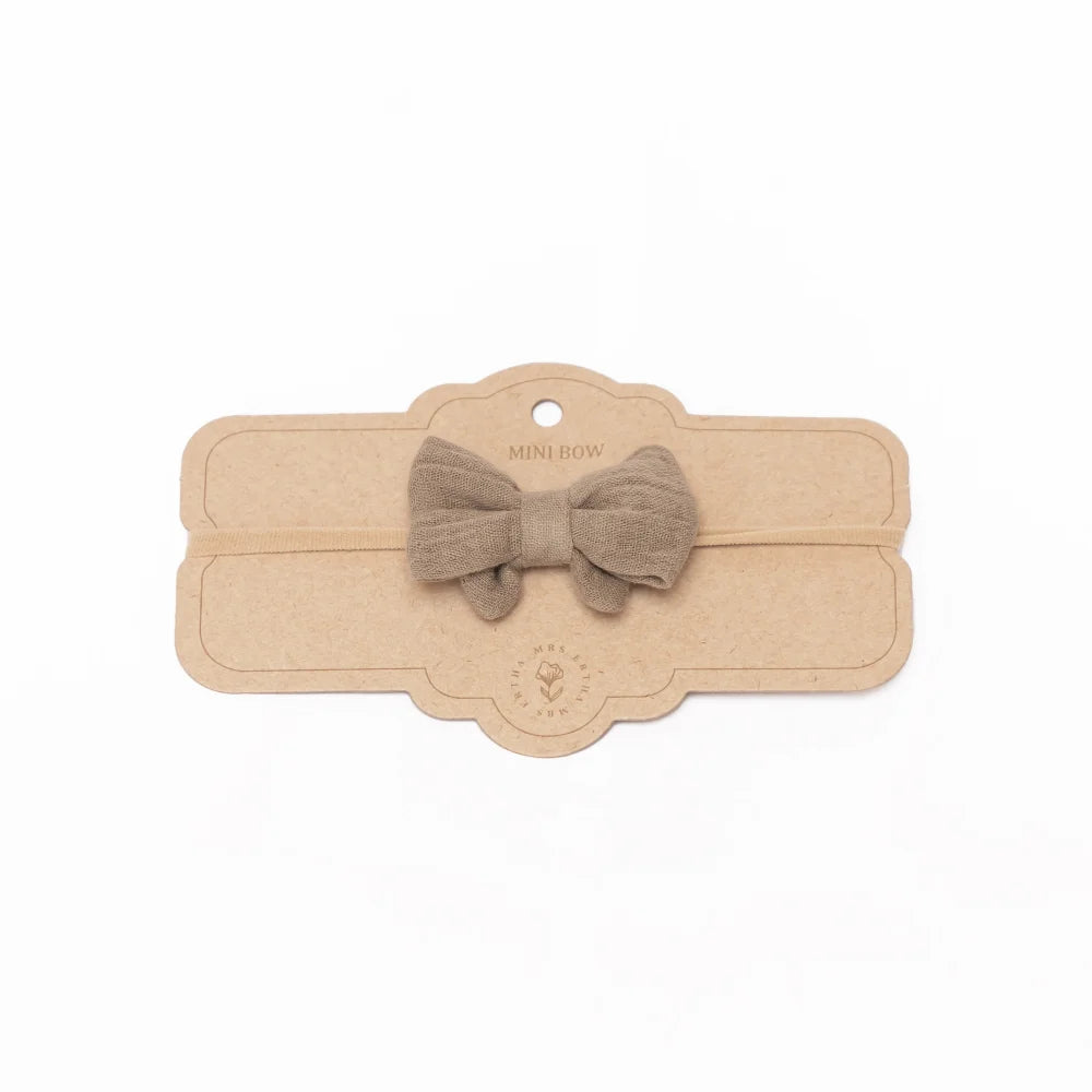 Beige Stoffschleife an einer dekorativen Holztafel für das Little Bow Stirnband Olive