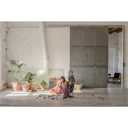 Weiße Ziegelwand mit Topfpflanzen und Spielzeug am Boden im Lola-Produkt