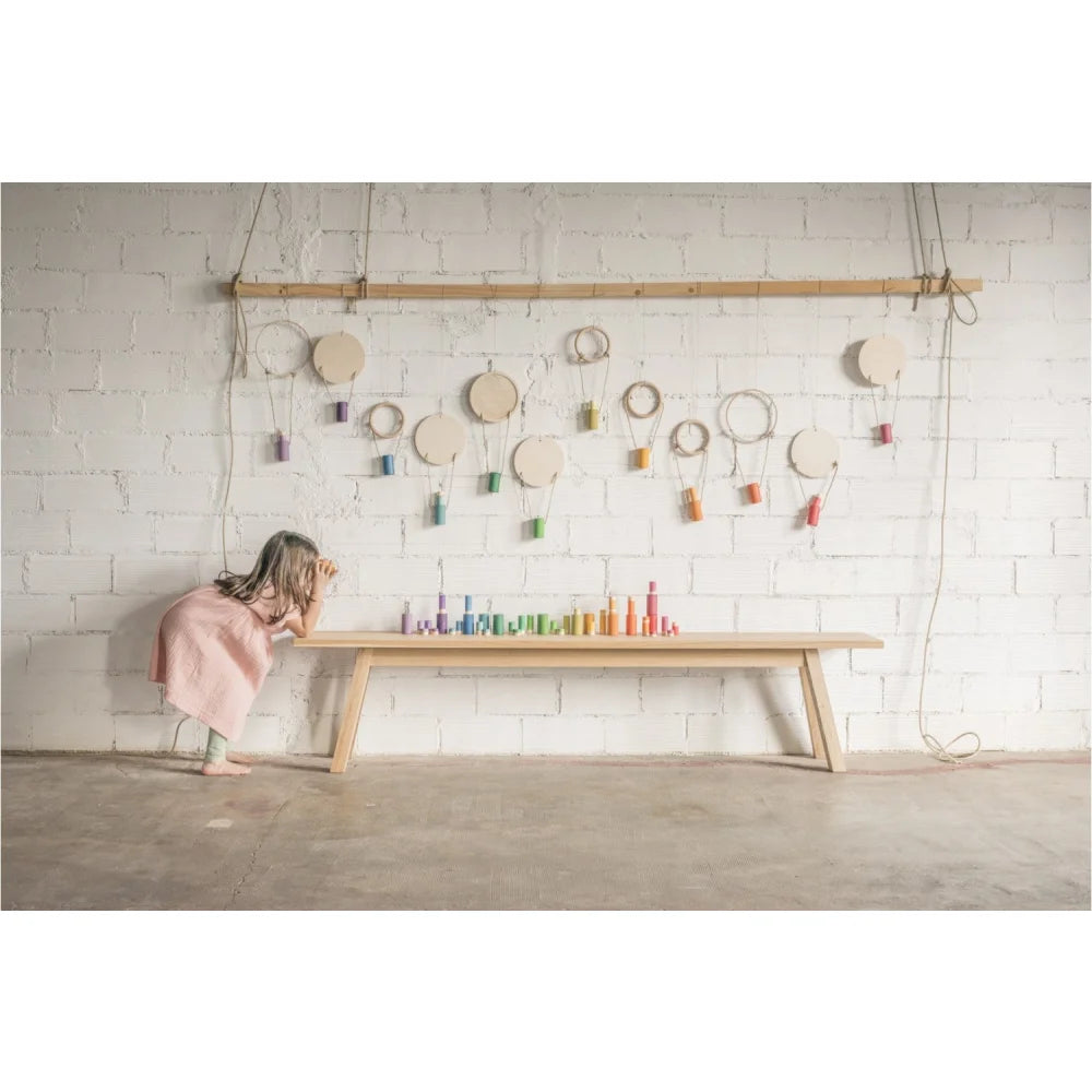 Holzbank Lola mit bunten Bauklötzen und Fadenrollen an der Wand