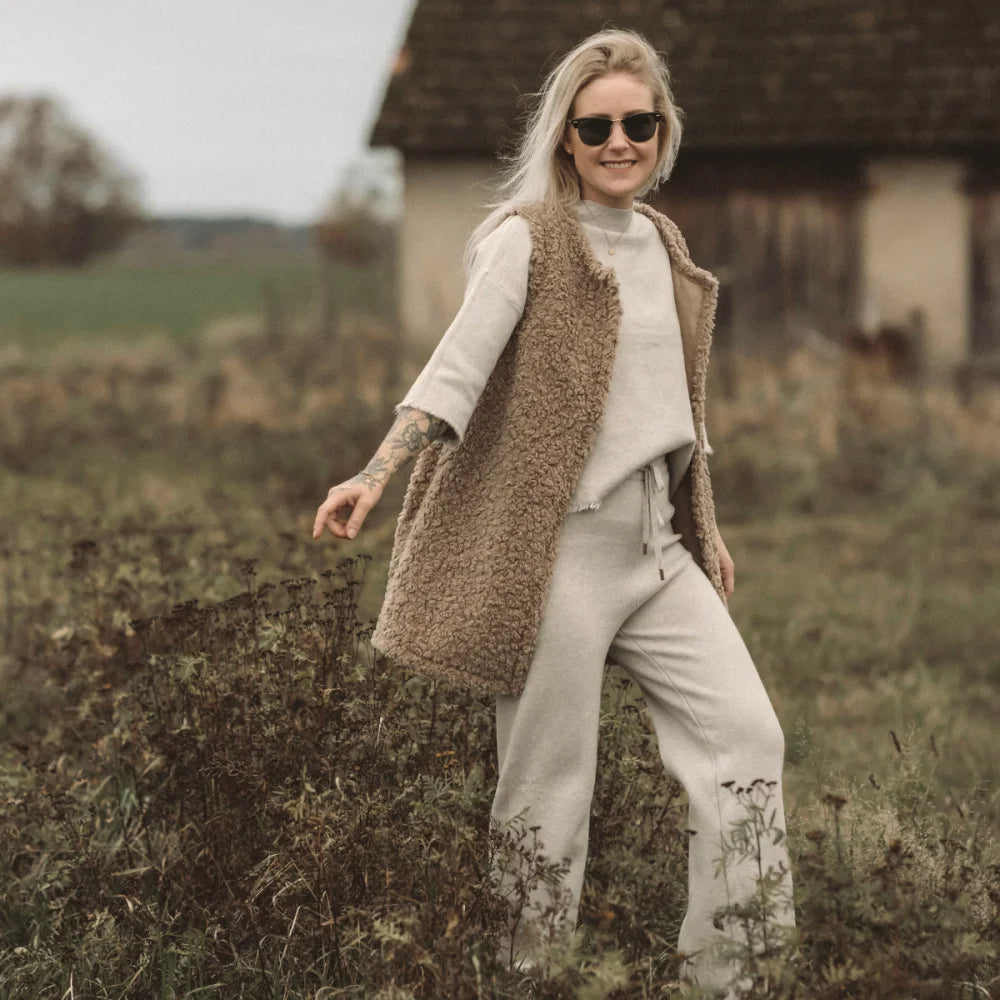 Person in braunem Teddywesten über cremefarbenem Pullover und passenden Hosen