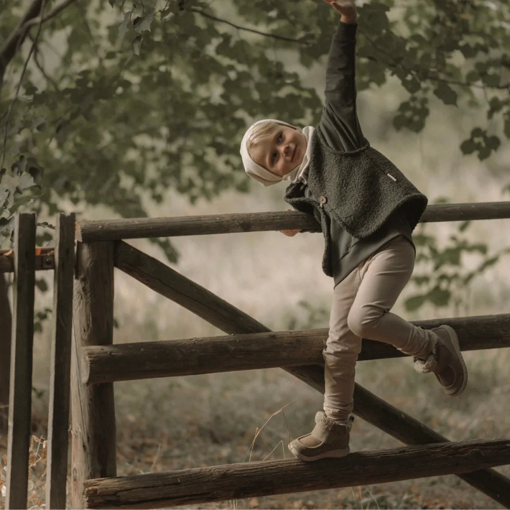 Ein junges Kind in gemütlicher Kleidung klettert einen Holzzaun hinauf