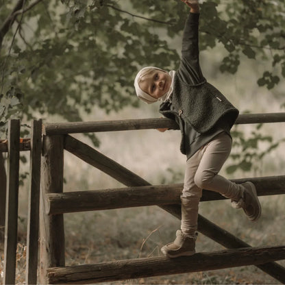 Ein junges Kind in gemütlicher Kleidung klettert einen Holzzaun hinauf