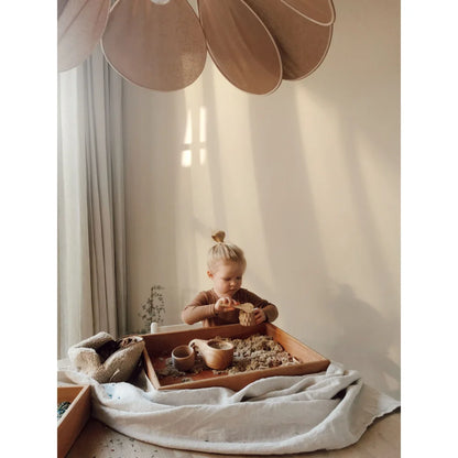 Kind eines Kindes beim Spielen mit Magic Sand in einem Sensorik-Behälter mit Sand und Holzbechern