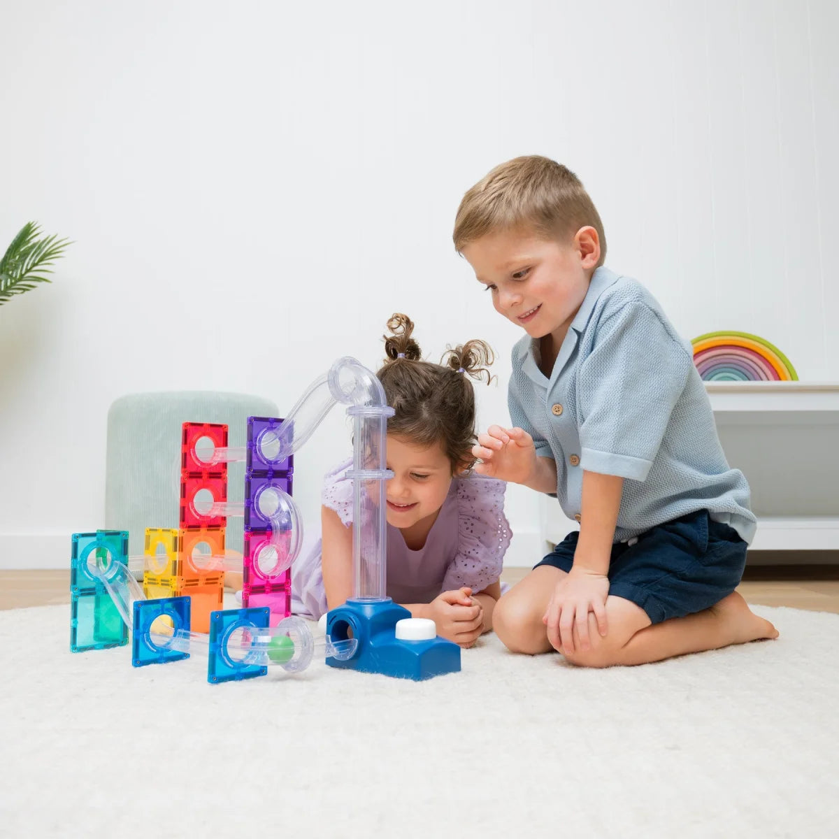 Zwei Kinder bauen am Boden eine Connetix Kugelbahn mit Launcher Pack