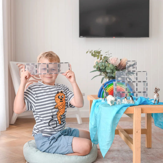 Ein Kind spielt mit transparenten Magnetbausteinen in rechteckiger Form