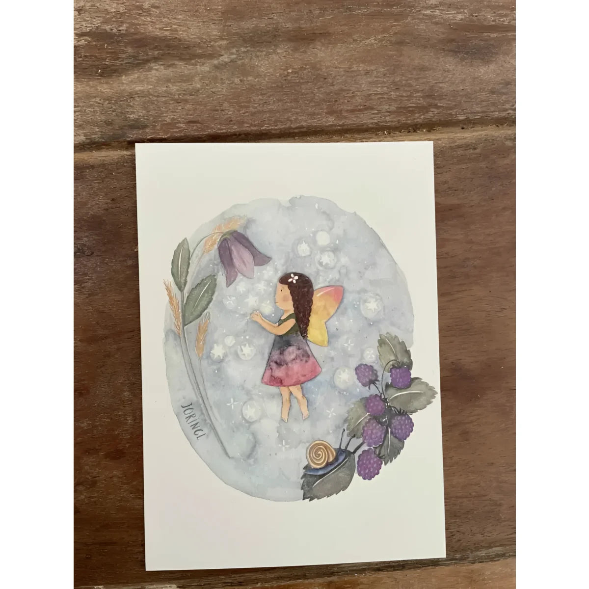 Eine delicate aquarellkarte mit einer fee in gelben flügeln und rosa kleid umgeben von beeren und blättern für geschenke für neugeborene