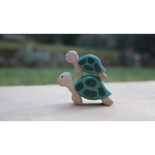 Zwei gestapelte hölzerne Meeresschildkröten, groß und klein, mit teal Schalen und dunklen grünen Flecken