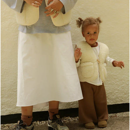 Creamfarbige, kuschelige merino mama gilet aus schaffell mit frontverschluss und zwei seitentaschen für nachhaltige babykleidung schweiz