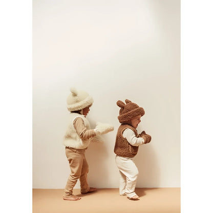 Zwei Kleinkinder in flauschigen tierförmigen Outfits und Hüten, die sich gegenüberstehen