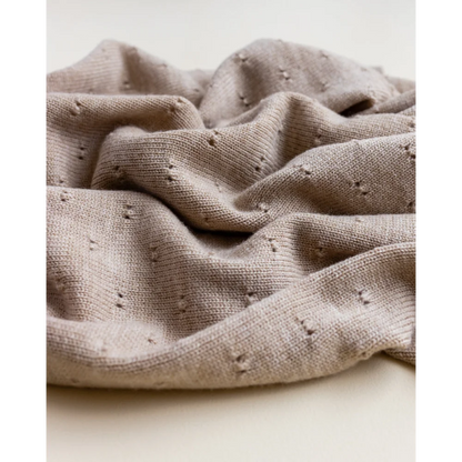 Crumpled beige Merino Strickdecke Bibi mit kleinen Löchern auf der Oberfläche