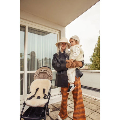 Frau mit Kind neben Kinderwagen auf Terrasse mit Merino Weste Milk