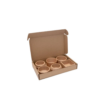 Offene Pappkartonbox mit sechs unglasieren Keramikschalen in verschiedenen Formen