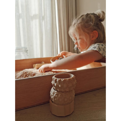 Kind eines Kindes beim Spielen mit einer Mini-Spielschale und Sand im Sensory Bin