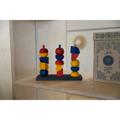 Moderner stapelspielzeug y mit drei bunten holz-geometrieformen auf dunkler basis als geschenk für neugeborene