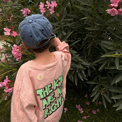 Gänseblümchen-Sticker auf dem Rücken eines rosa Kindershirts im Garten