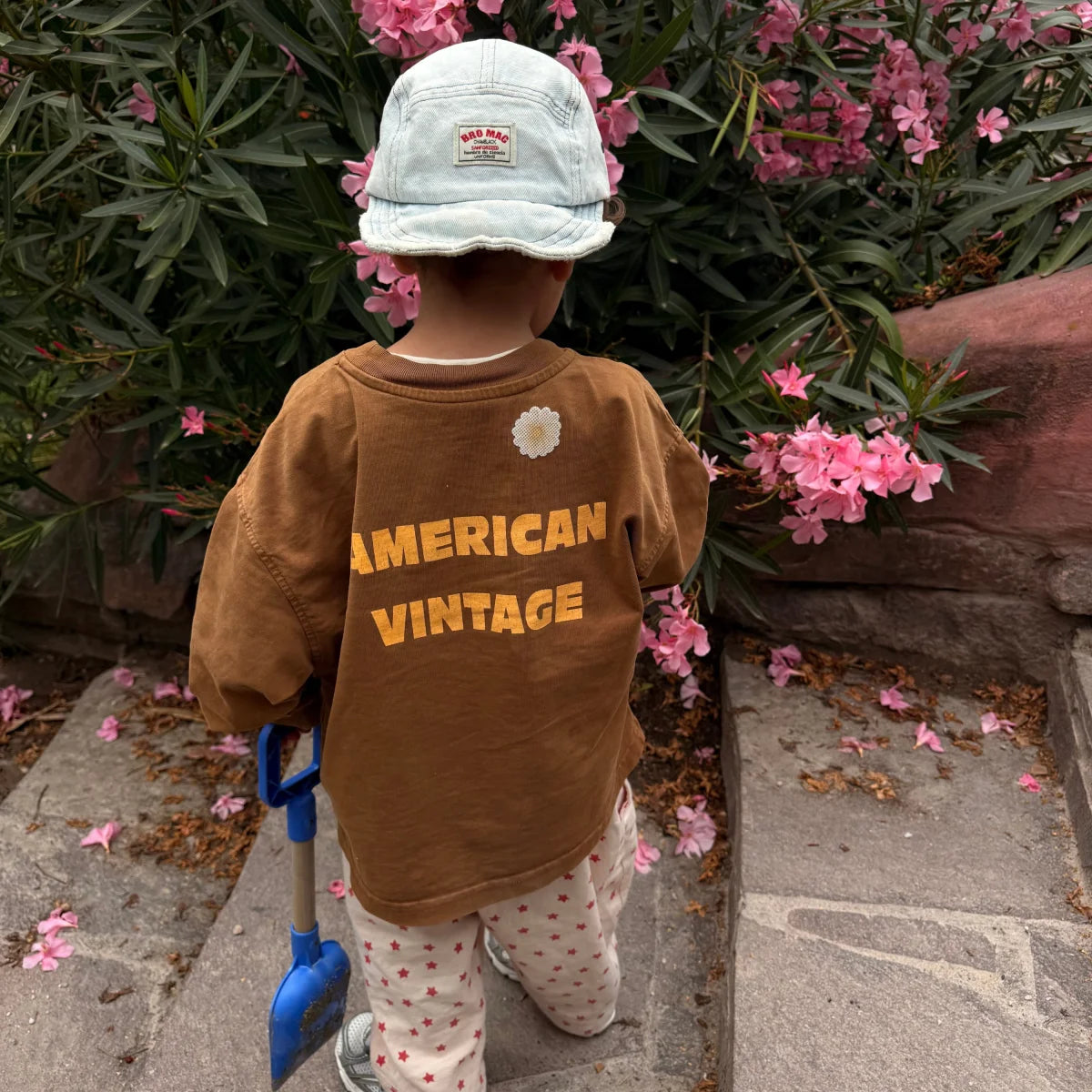 Kleinkind mit Gänseblümchen-Sticker auf dem Pullover beim Gärtnern