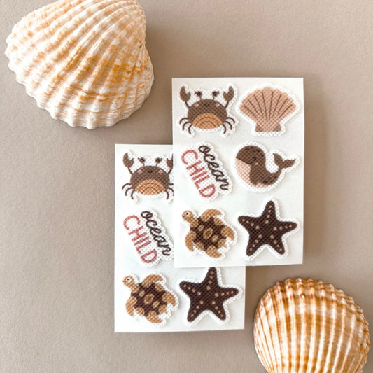 Ein set von meeresthema-stickern mit niedlichen braunen und beigen meerestieren wie krabben, schildkröten, walen und seesternen, weiß umrandet, mückenschutz ocean child edition