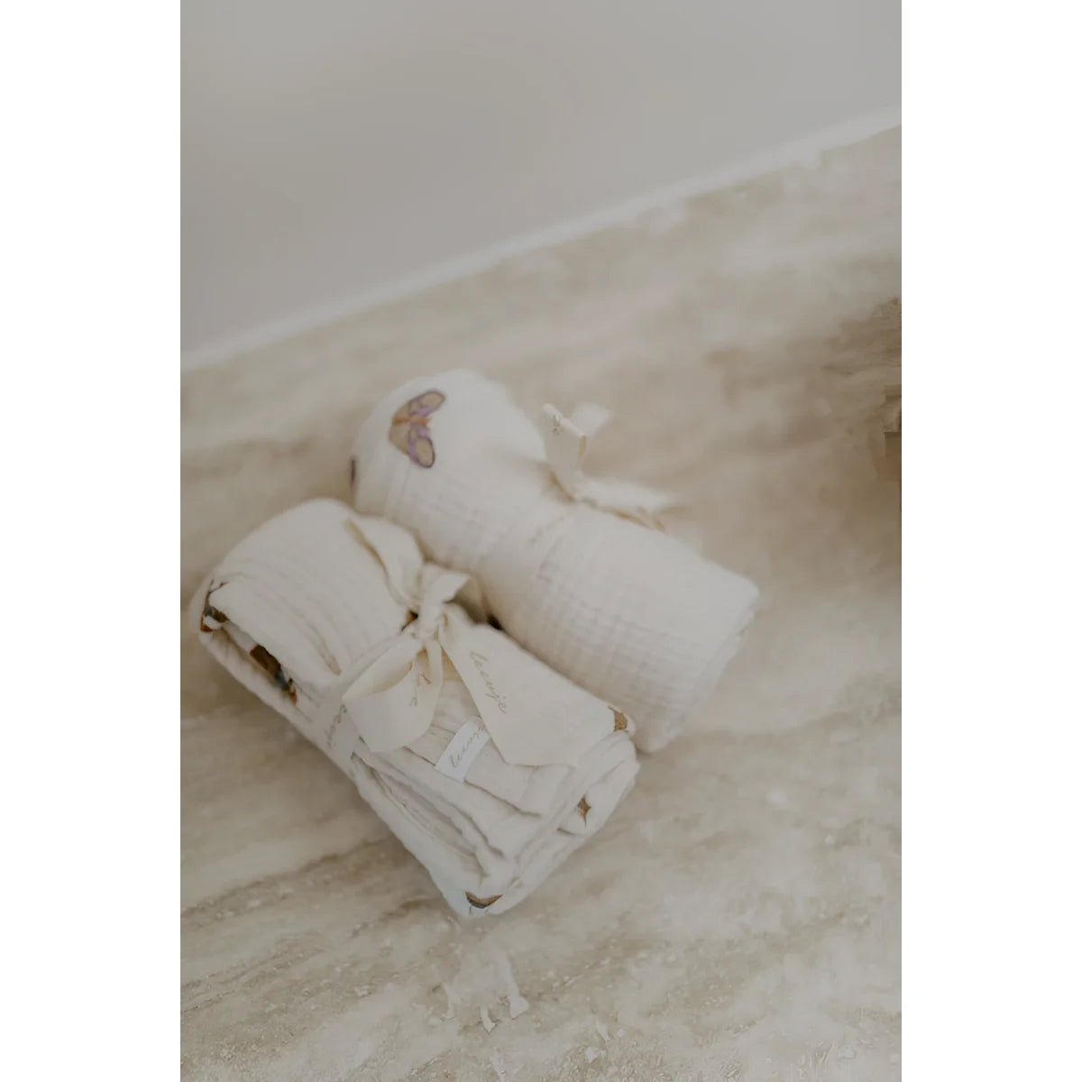 Zwei gerollte, offwhite musseletücher 70x70 cm mit herz- und blattmustern, nachhaltige babykleidung schweiz