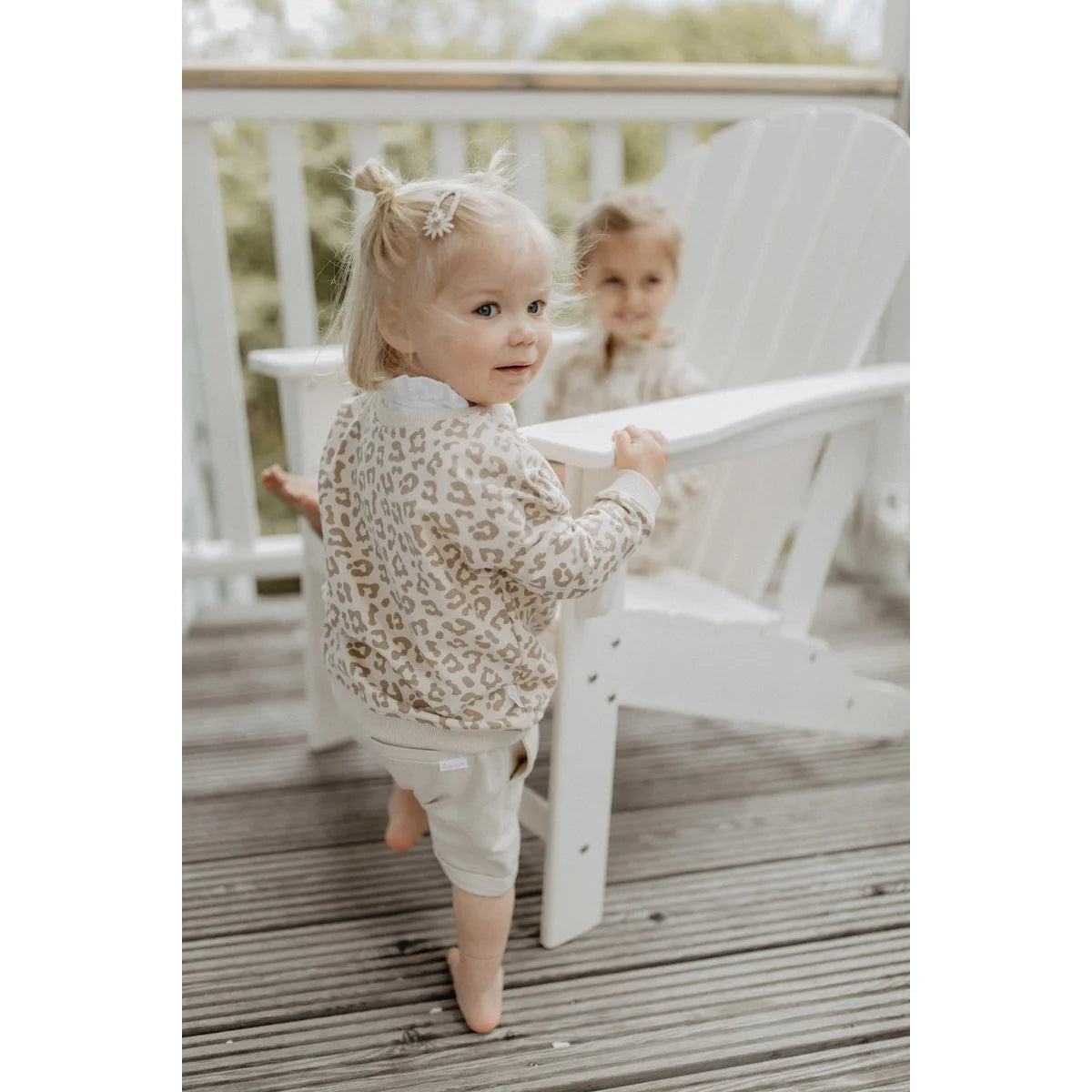 Ein kleinkind trägt einen beige leo oversize pullover aus nachhaltiger babykleidung schweiz passend als geschenk für neugeborene